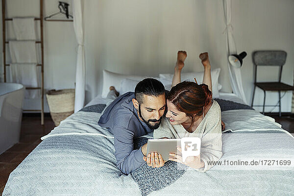 Ein Paar benutzt ein digitales Tablet  während es zu Hause im Bett liegt