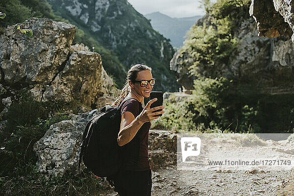 Lächelnde Trekkerin  die beim Wandern ein Selfie mit ihrem Smartphone macht