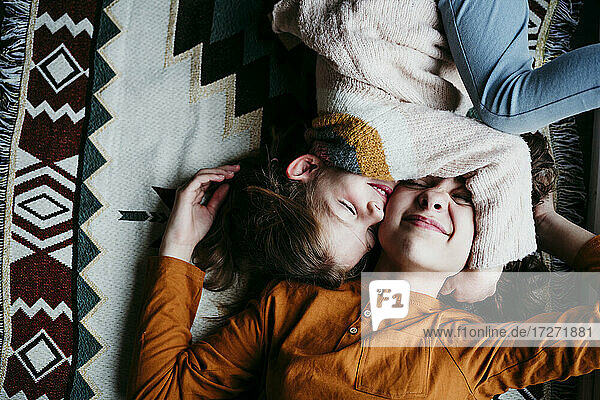 Mädchen umarmt Schwester Gesicht  während auf der Decke zu Hause liegen