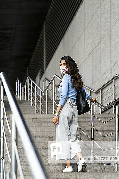 Nachdenkliche Frau mit Handtasche beim Treppensteigen während COVID-19