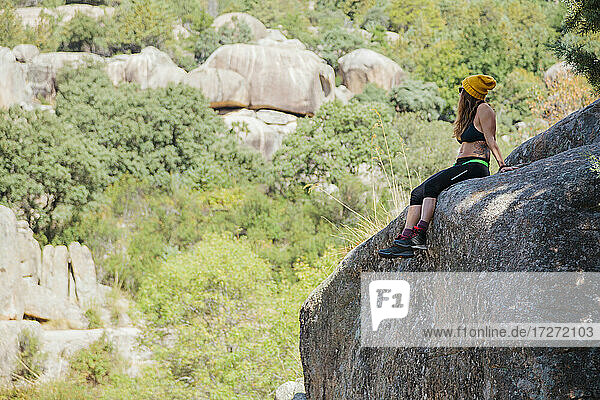 Wanderer betrachtet die Aussicht  während er sich auf einem Felsen im Wald bei La Pedriza  Madrid  Spanien  ausruht