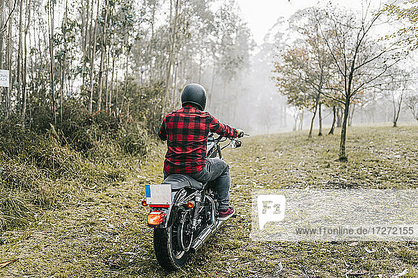 Mann beim Motorradfahren im Wald bei nebligem Wetter