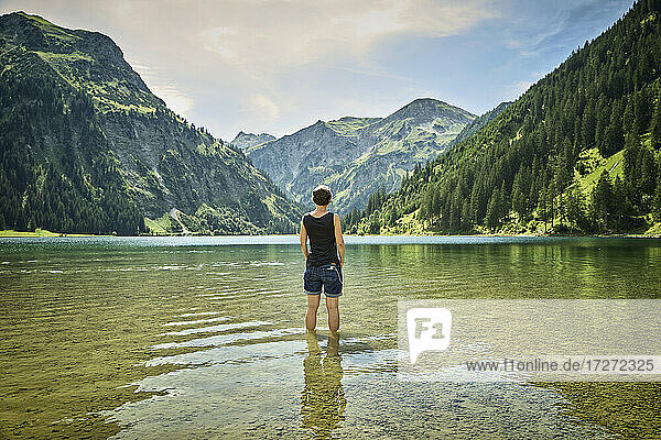 Mature woman standing knee deep in Vilsalpsee while looking at mountain range on sunny day