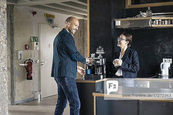 Lächelnde Geschäftsleute  die eine Kaffeepause machen  während sie in der Cafeteria im Büro stehen