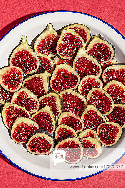 Directly above shot of fig slices arranged in plate on red background