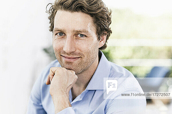 Smiling man with hand on chin sitting in office
