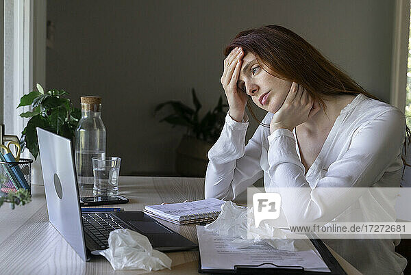 Sick woman talking to doctor on laptop at home   having a headACHE
