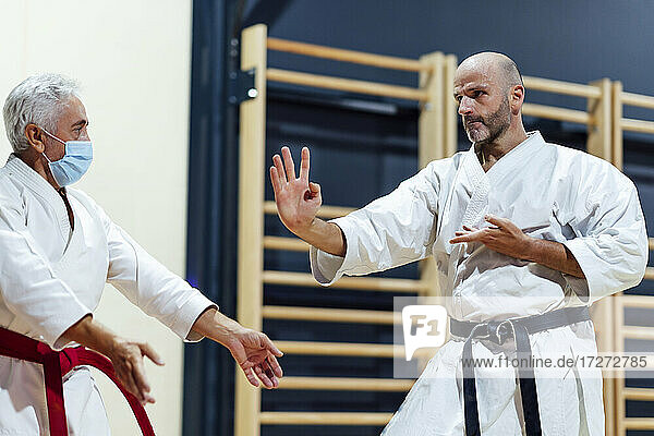 Männlicher Schüler übt Karate mit seinem Ausbilder im Unterricht