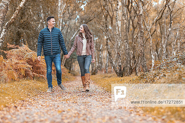 Glückliches heterosexuelles Paar  das im Herbst im Park spazieren geht