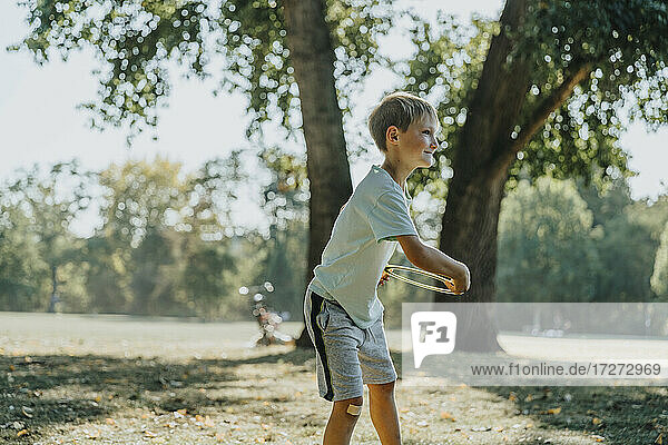 Kleiner Junge wirft Frisbee-Ring  während er in einem öffentlichen Park an einem sonnigen Tag steht