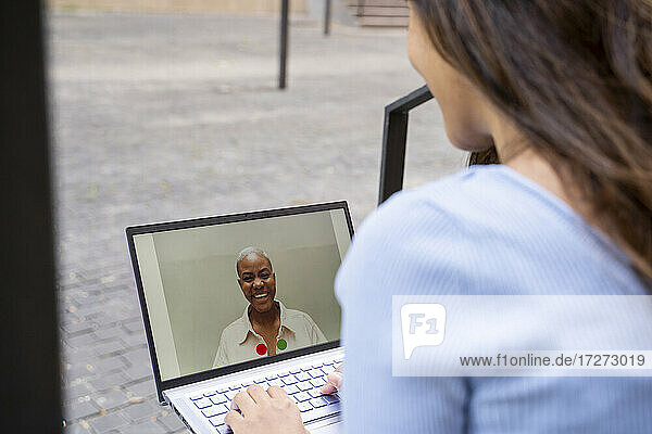 Geschäftsfrau führt Videogespräche über einen Laptop  während sie im Freien sitzt