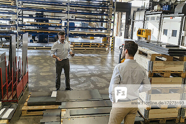 Business people standing by equipment while having discussion at factory