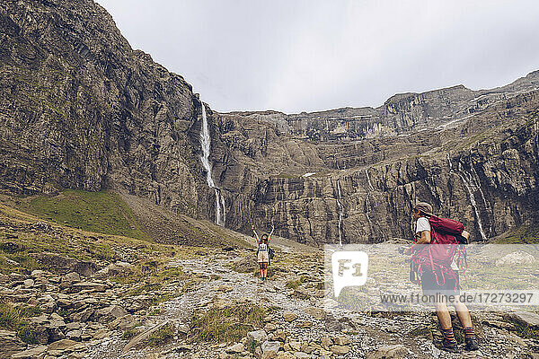 Mann fotografiert Frau  die vor einem Wasserfall steht