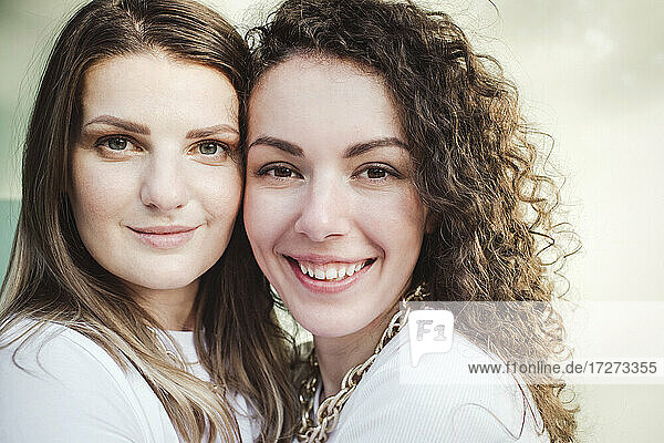 Smiling female friends with cheek to cheek