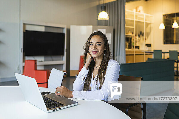 Selbstbewusste Geschäftsfrau mit Laptop am Schreibtisch im Büro