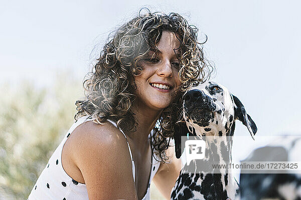 Lächelnde junge Frau mit Dalmatinerhund an einem sonnigen Tag