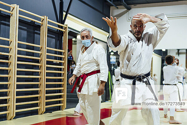 Ausbilder von männlichem Schüler  der Karate im Unterricht übt