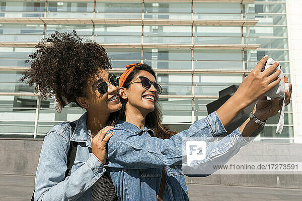 Lächelnde Freunde  die ein Selfie mit der Kamera machen  während sie auf dem Dach stehen