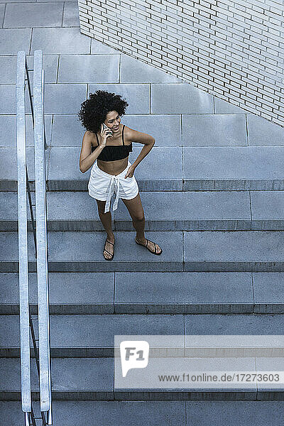 Junge Frau benutzt ihr Smartphone  während sie auf einer Treppe steht