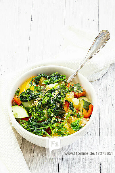 Schüssel mit warmem veganen Quinoa-Salat mit Spinat  Paprika  Gurken  Tomaten  Petersilie und Minze
