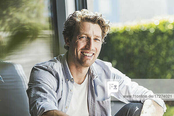 Mid adult man smiling while sitting in house
