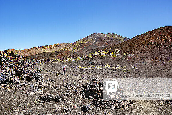 Senior man hiking along trail stretching across brown barren landscape of Tenerife island