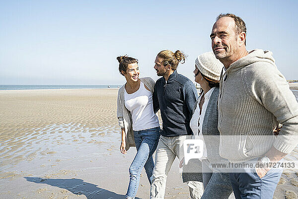 Lächelnde Paare  die zusammen am Strand spazieren gehen