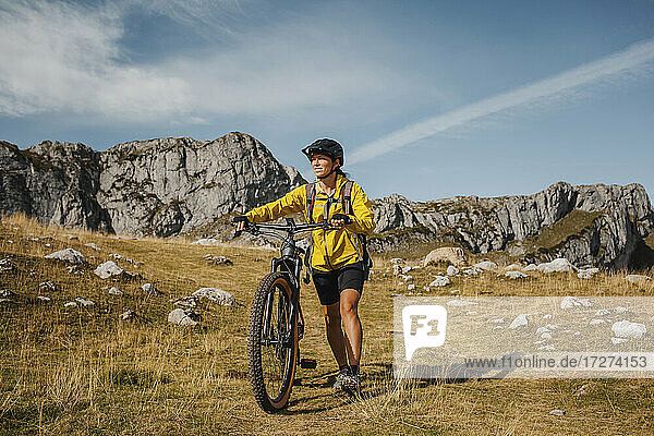 Mittlere erwachsene Frau mit Fahrrad vor einem Berg im Naturpark Somiedo  Spanien