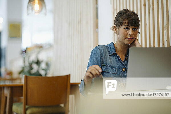 Weiblicher Besitzer konzentriert sich bei der Benutzung eines Laptops in einem Cafe