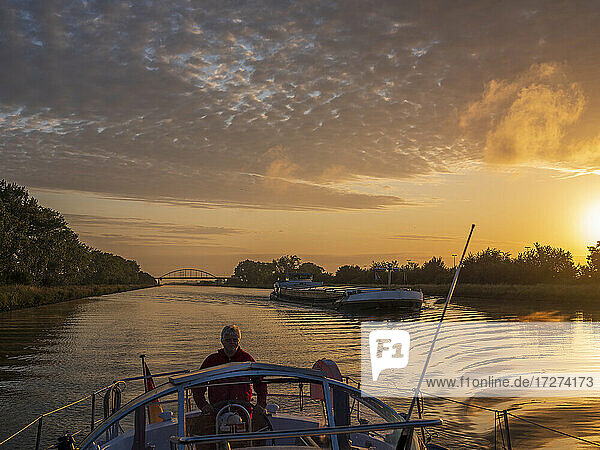 Mann  der bei Sonnenaufgang auf dem Juliana-Kanal segelt