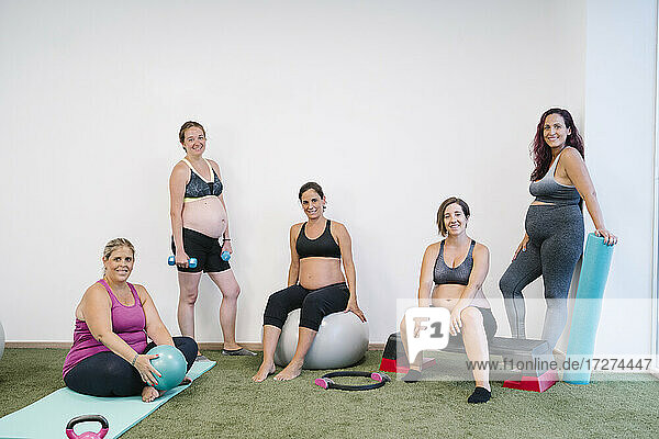 Lächelnde Gruppe schwangerer Frauen bei Übungen im Yogastudio