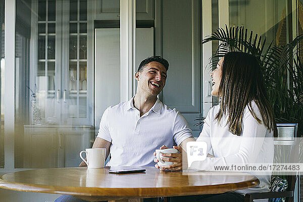 Lächelndes Paar  das zu Hause zusammen sitzt und Kaffee trinkt