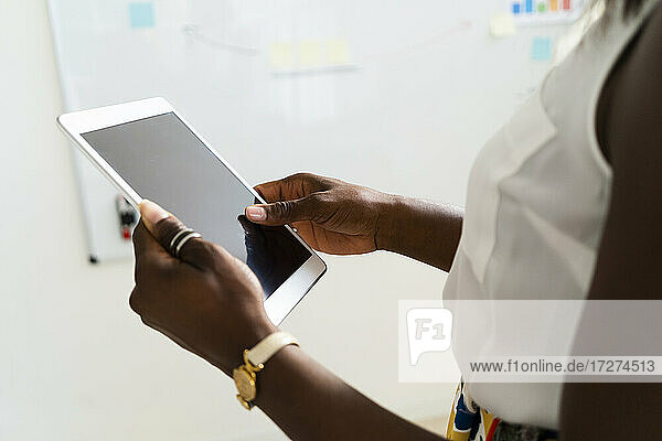 Businesswoman holding digital tablet while standing at office