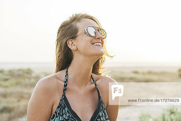 Lächelnde schöne Frau mit Sonnenbrille  die im Urlaub wegschaut