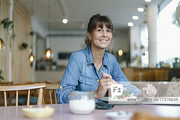 Weibliche Besitzerin beim Essen in einem Café
