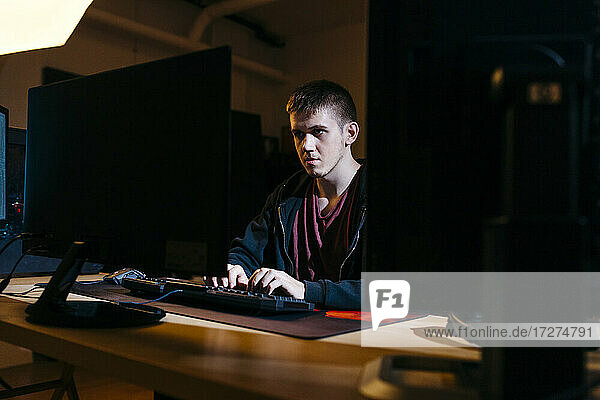 Junger Computerhacker bei der Arbeit  während er im Büro sitzt