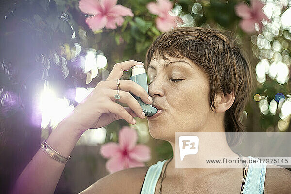Young woman breathing through asthma inhaler