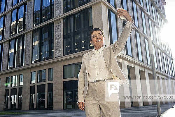 Geschäftsfrau  die Selfie  während stehend gegen moderne Bürogebäude
