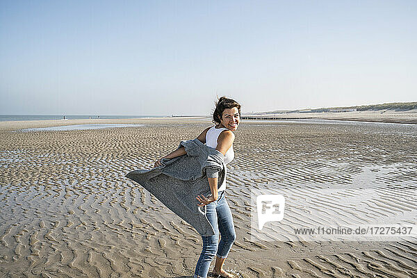 Unbekümmerte junge Frau am Strand gegen den klaren Himmel an einem sonnigen Tag