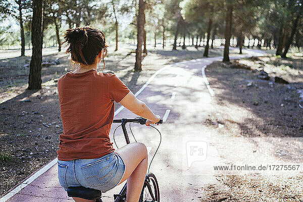 Woman riding bicycle at countryside during sunny day