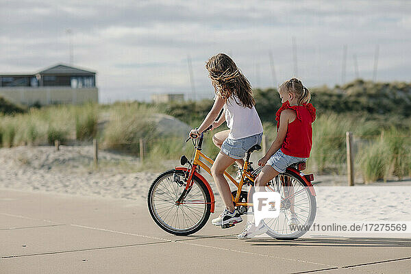 Sisters riding on bicycle during sunny day