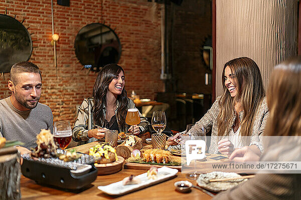 Lächelnde Freunde  die Essen und Trinken genießen  während sie am Tisch im Restaurant sitzen