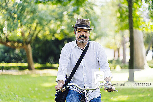 Älterer Mann lächelt beim Radfahren im Park