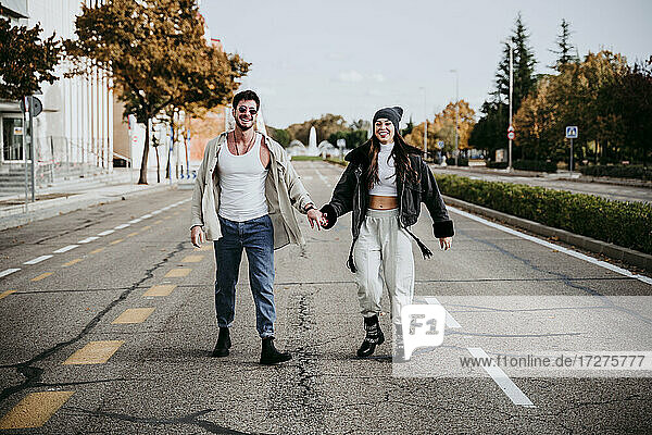 Schöne lächelnde Frau hält Hände mit männlichen Partner  während auf der Straße in der Stadt stehen
