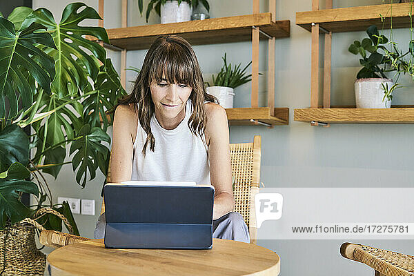 Reife Frau  die ein digitales Tablet benutzt  während sie zu Hause sitzt