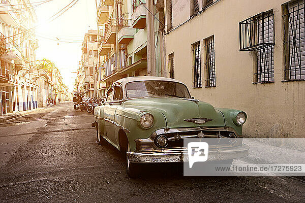 Kuba  Provinz La Habana  Havanna  Pastellgrüner Oldtimer  geparkt auf der Straße bei Sonnenuntergang