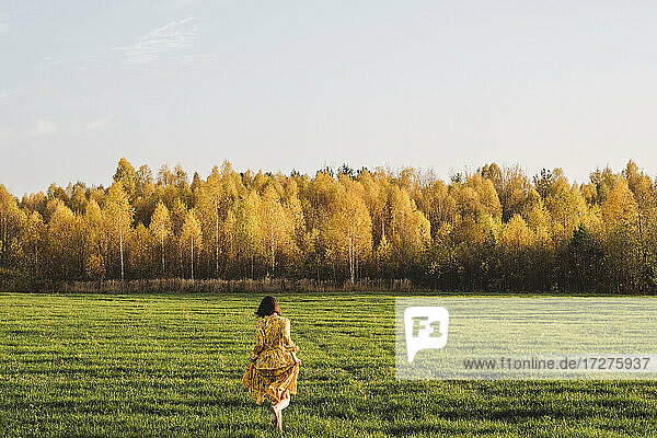 Mid erwachsene Frau zu Fuß auf Gras im Herbst Feld an einem sonnigen Tag