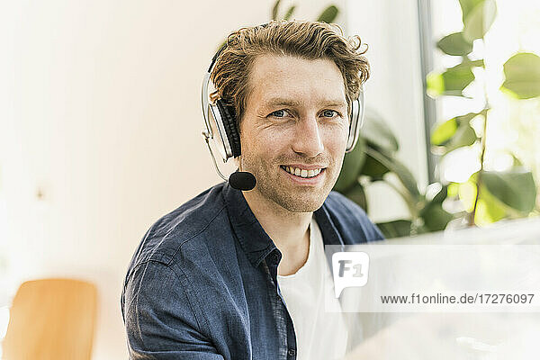 Smiling mid adult man wearing headphone sitting at home