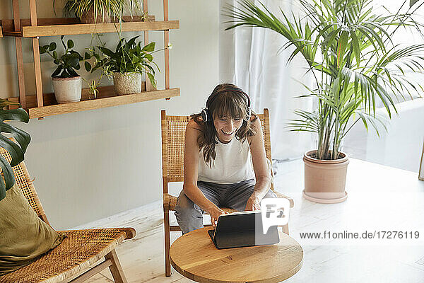 Smiling mature woman using digital tablet while sitting at home