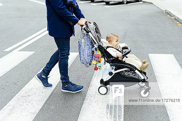 Man with baby stroller crossing road in city